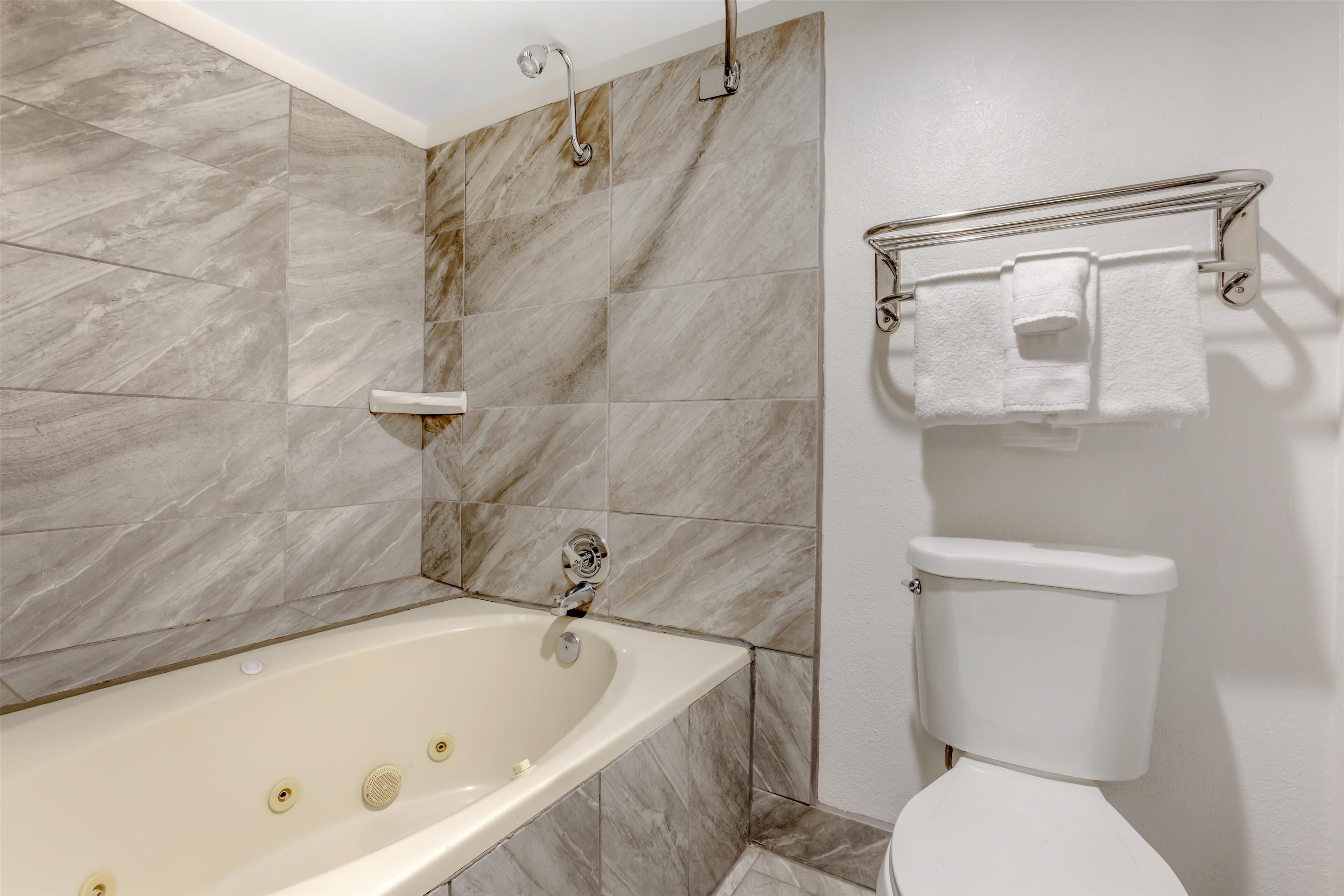 A bathroom with a bathtub, toilet, and towel rack.