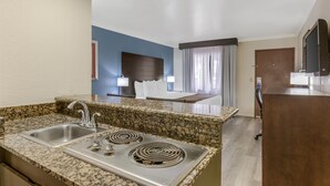 Una cocina moderna con encimeras de granito, un fregadero de acero inoxidable y una placa de cocina integrada.