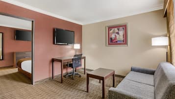 A hotel room with a bed, a desk, a chair, a TV, a lamp, and a couch.