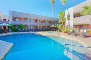 A hotel pool area with a clear blue pool, lounge chairs, and palm trees. - Best Western InnSuites Tucson Foothills Hotel & Suites (Tucson)