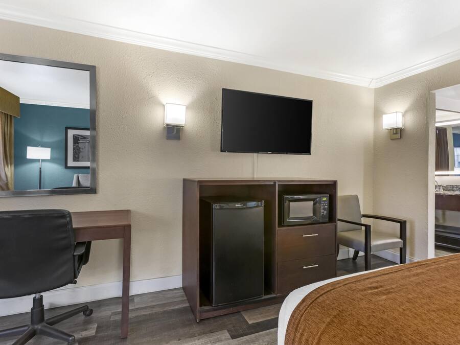 Habitación de hotel con escritorio, silla de oficina, televisión de pantalla plana, minibar y una cama.