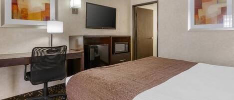 A hotel room with a bed, desk, chair, television, and artwork on the walls.
