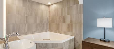 Un baño moderno con una bañera independiente, un lavabo y un mueble de tocador con espejo.