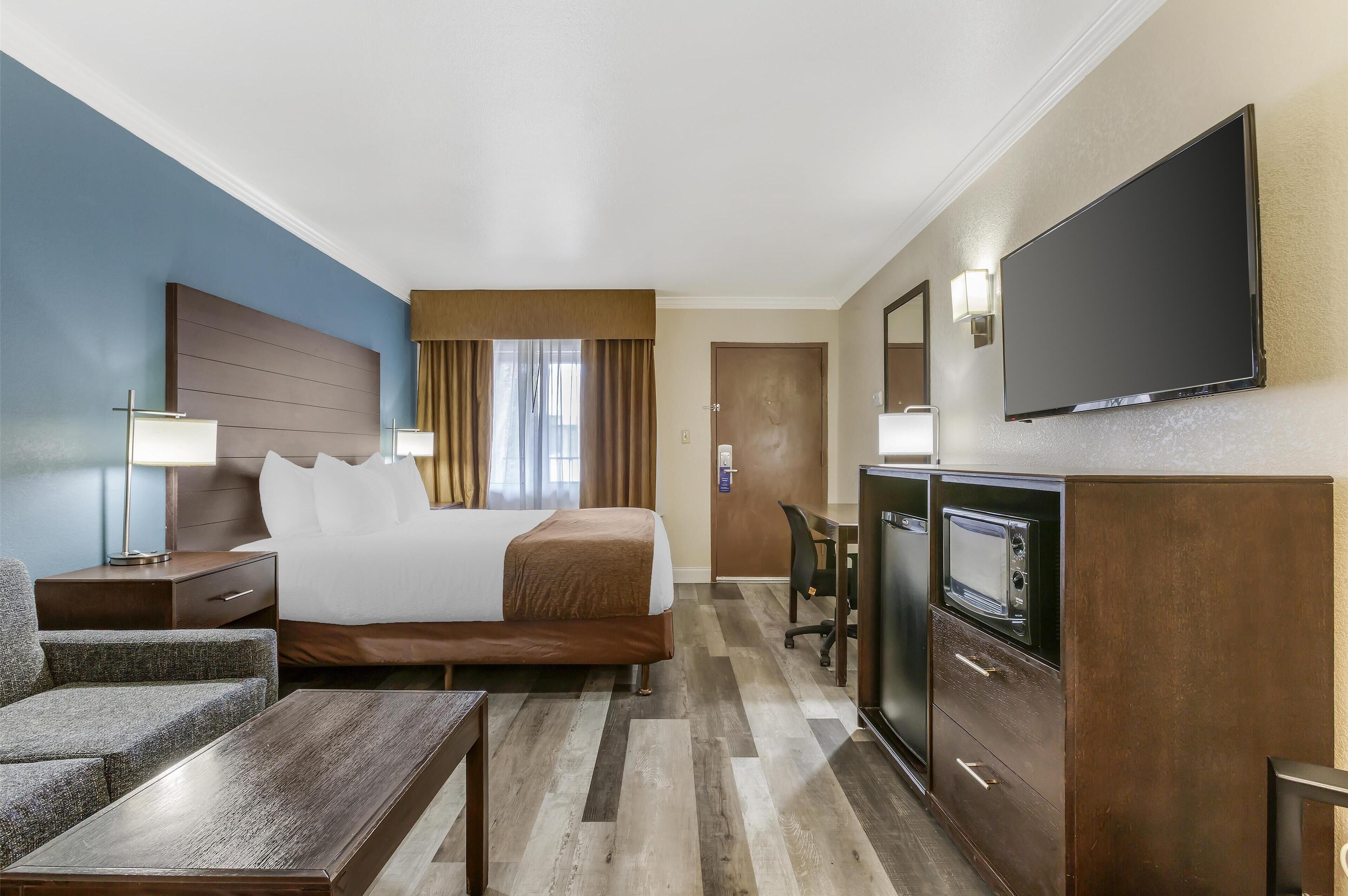 Une chambre d’hôtel équipée d’un lit, d’un bureau, d’une télévision, d’une chaise et d’une table de chevet.