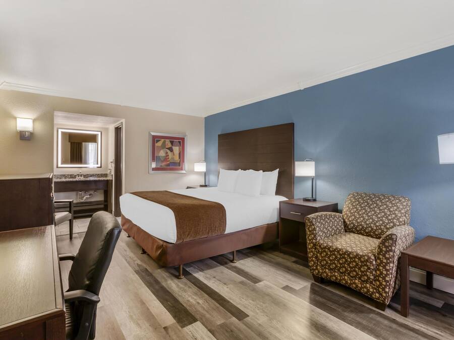 Een hotelkamer met een bed, bureau, stoel en een grote spiegel.