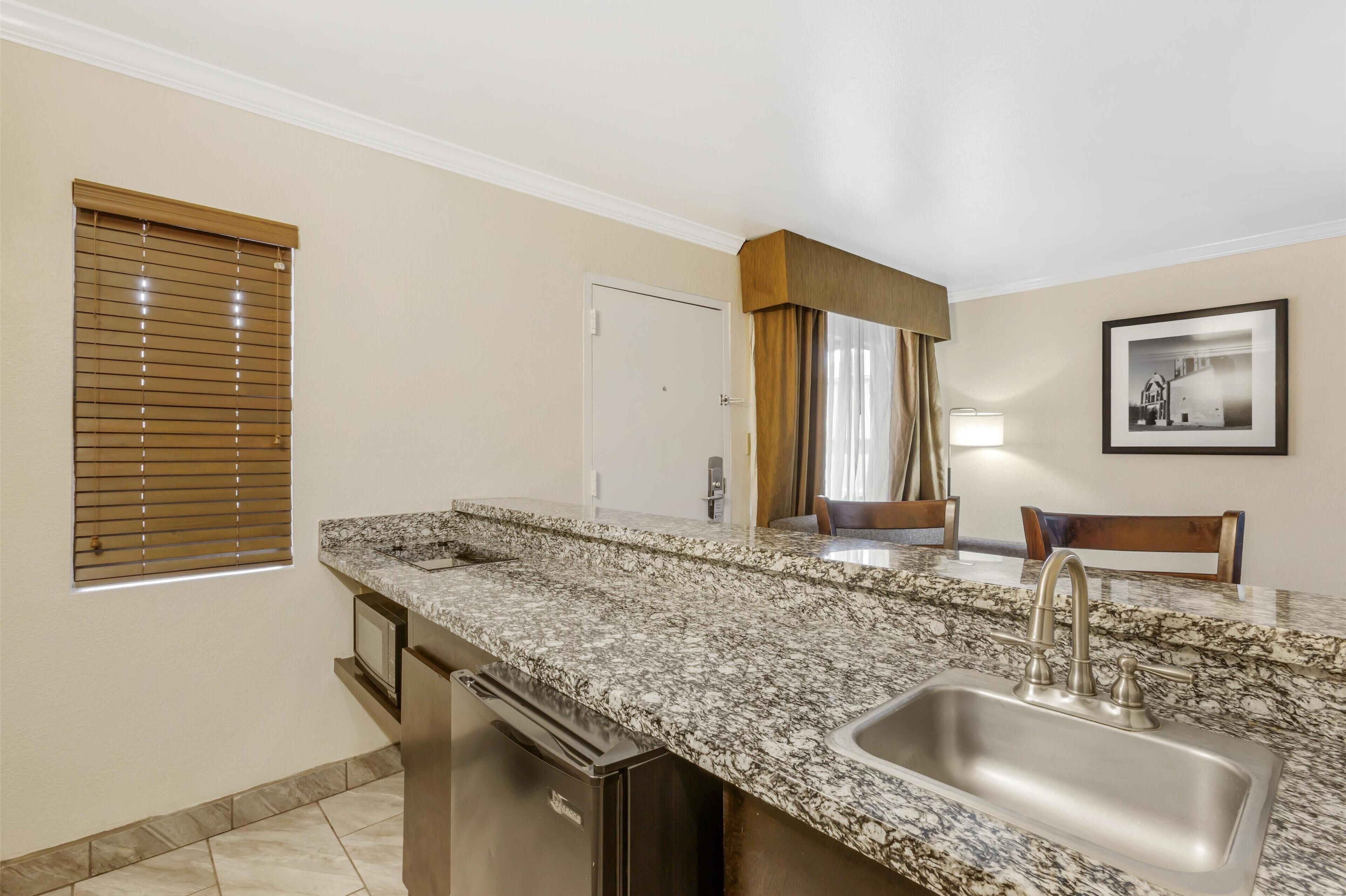 A kitchen with a granite countertop, stainless steel sink, and a dishwasher.