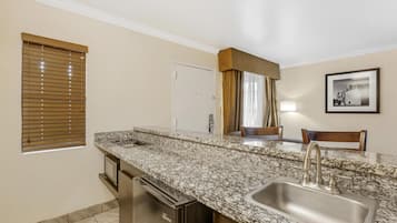 A kitchen with a granite countertop, stainless steel sink, and a dishwasher.