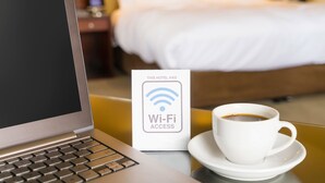 A laptop, a Wi-Fi access sign, and a cup of coffee on a table in a hotel room. - Trade Winds Inn Clinton (Clinton)