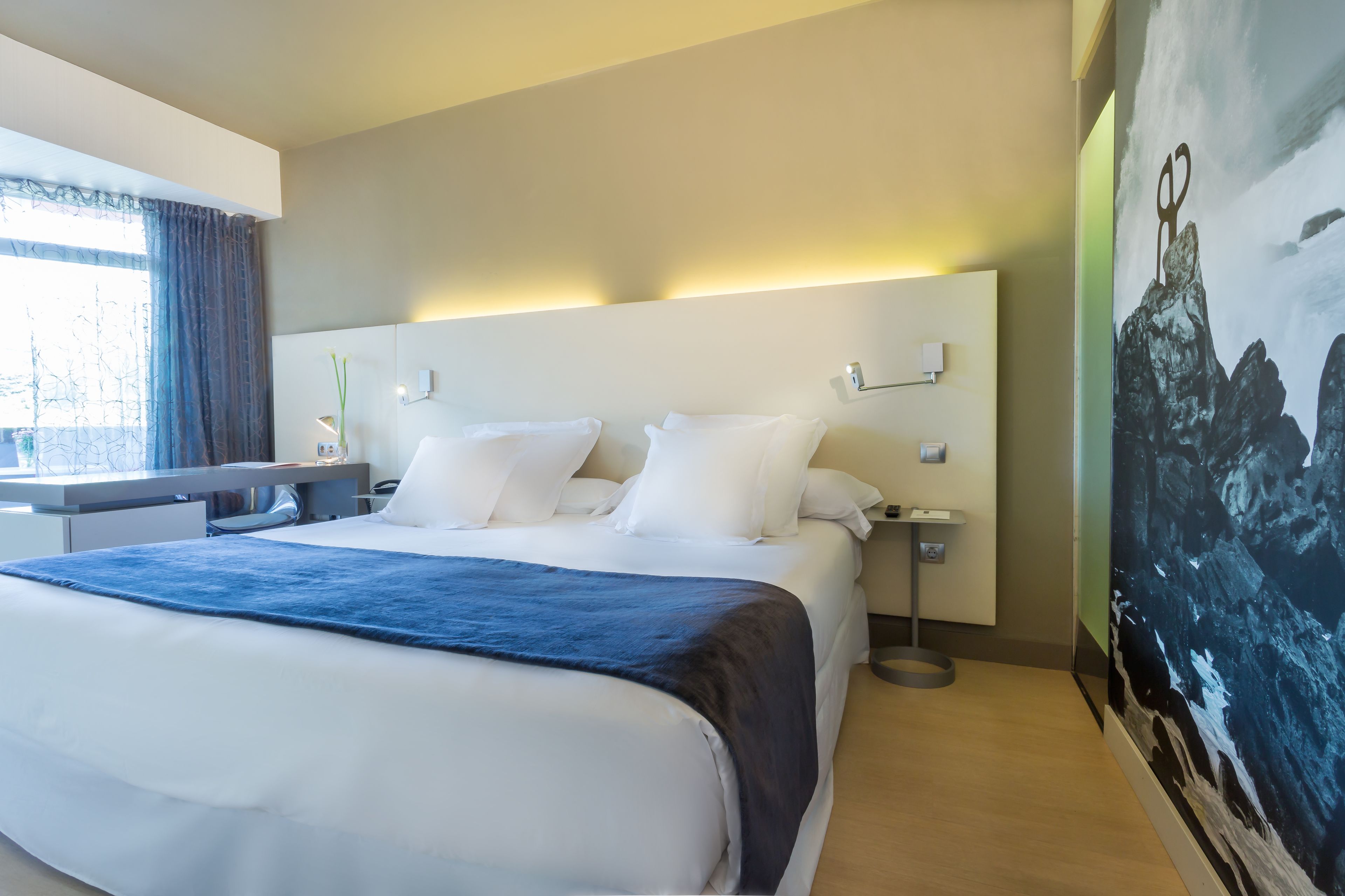 Een hotelkamer met een groot bed, een bureau en een schilderij aan de muur.