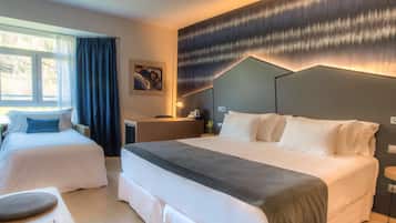 Habitación de hotel con dos camas, un escritorio y un ventanal grande con cortinas.