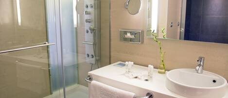 A modern bathroom with a glass shower enclosure, a white sink with a mirror above it, and a towel rack.