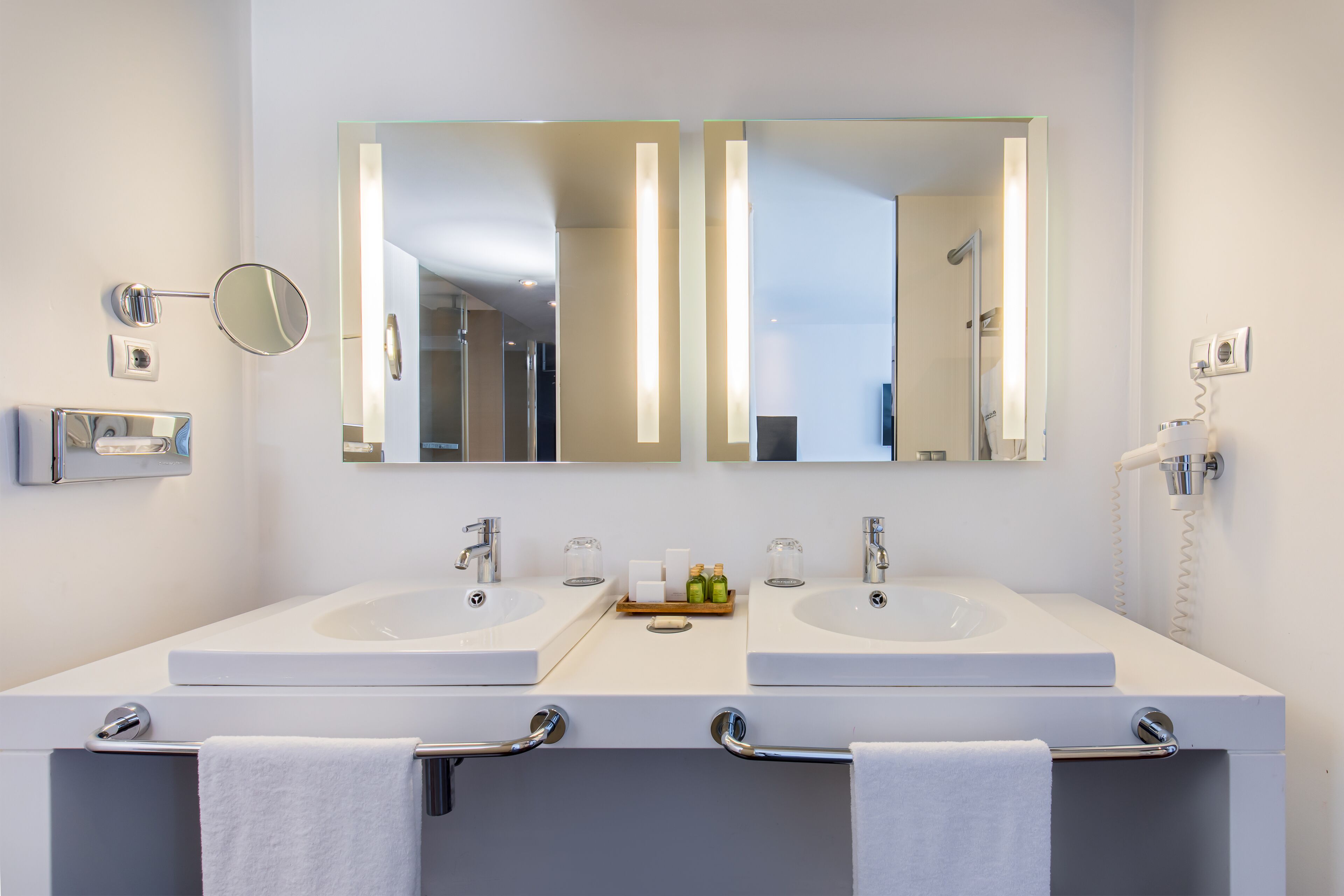 Een moderne badkamer met twee wastafels, een grote spiegel en een handdoekhouder.