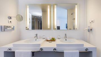 Un baño moderno con dos lavamanos, un espejo grande y un perchero para toallas.