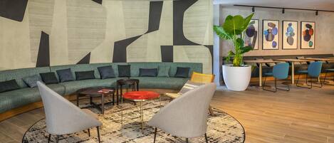 A modern lounge area with a curved sofa, two armchairs, a coffee table, and a large potted plant.