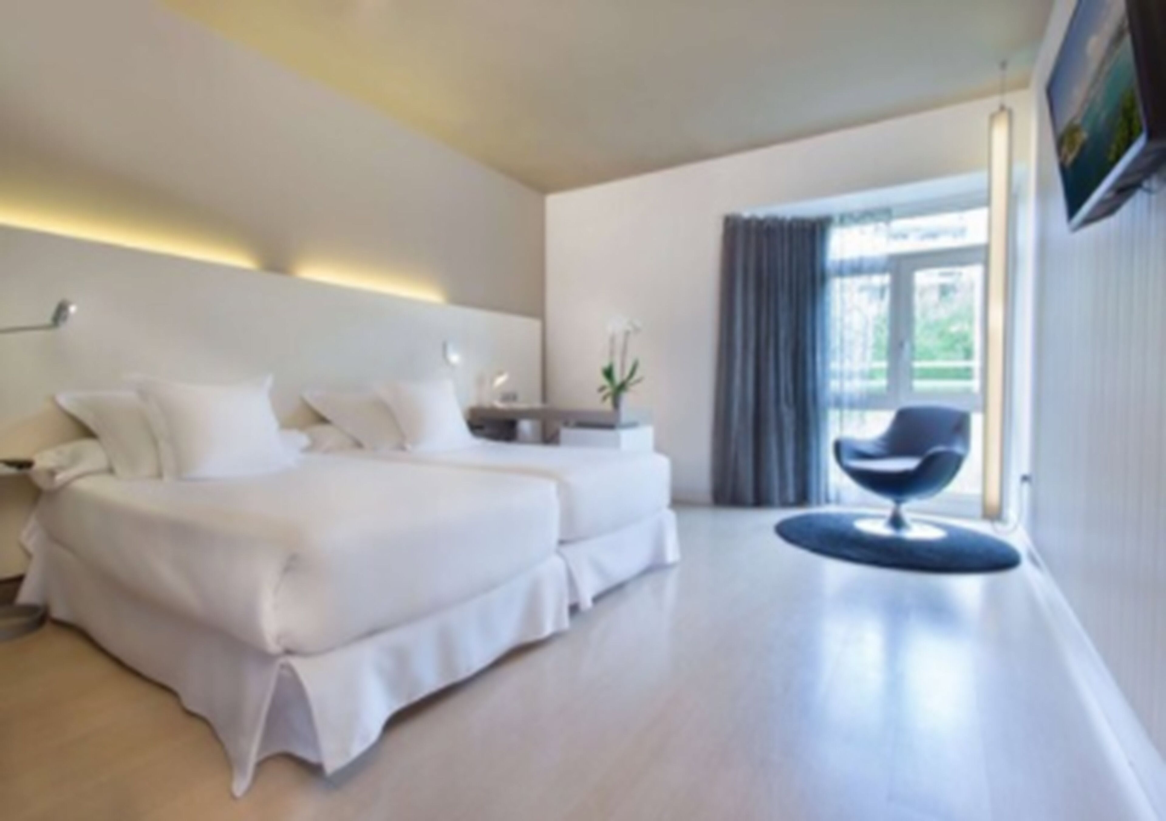 A modern hotel room with a large bed, a desk, and a chair.