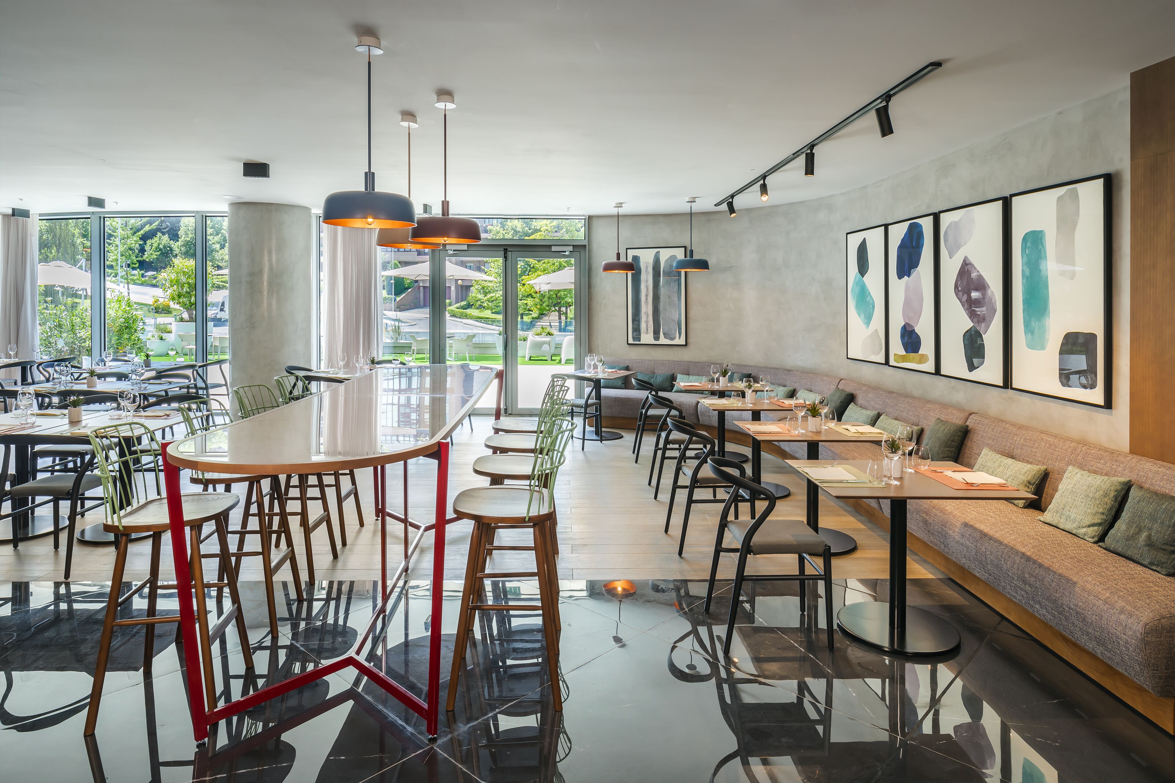 Un restaurant moderne doté d’un long bar, de plusieurs espaces de restauration et de grandes fenêtres offrant une vue sur l’extérieur.