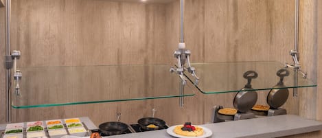 Un baño moderno con cabina de ducha de vidrio, tocador con espejo y barra de desayuno con diversos alimentos.