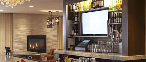 A bar area with a fireplace, bar counter, and shelves of liquor bottles.