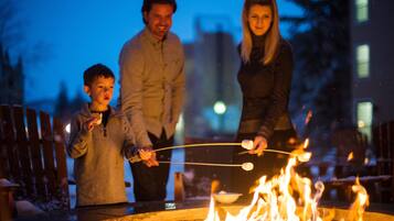 A family of three roasting marshmallows over a campfire.