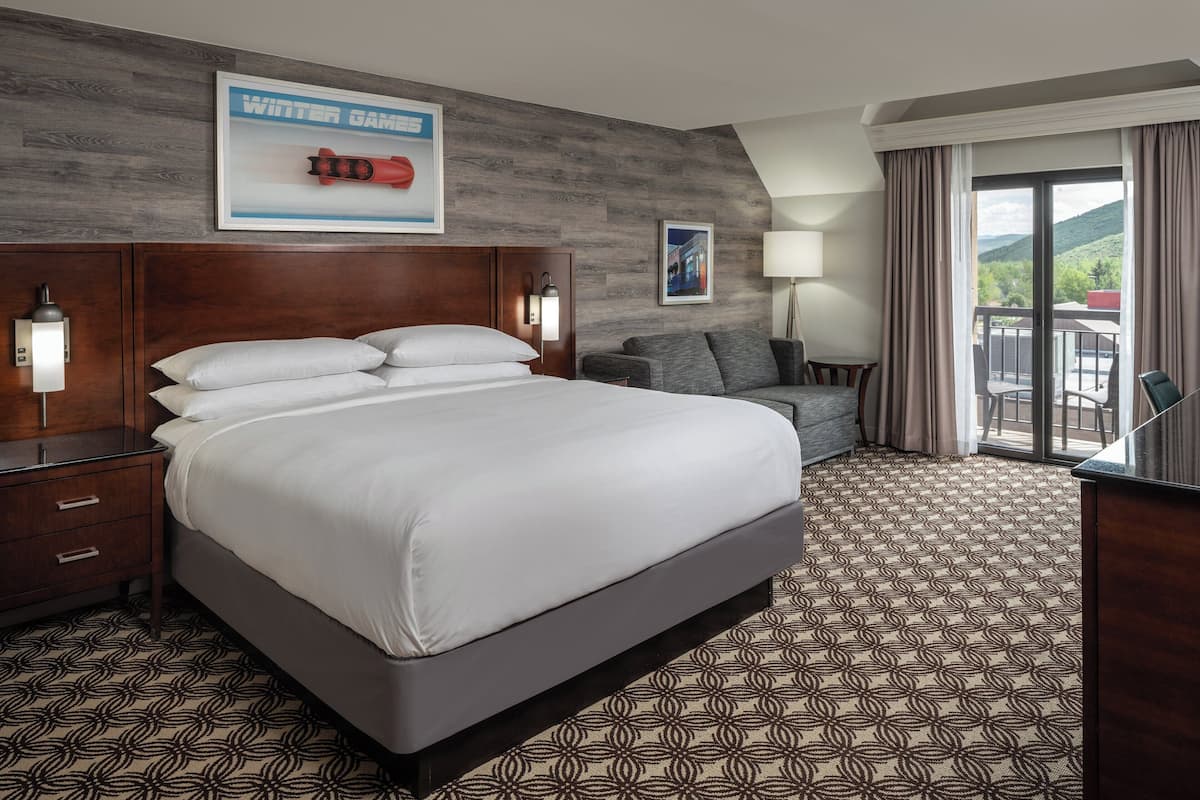 Habitación de hotel con una cama grande, un sofá, un escritorio y vistas al exterior.