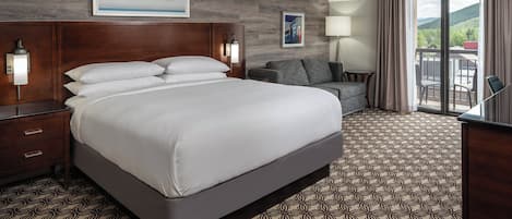 Une chambre d’hôtel avec un grand lit, un canapé, un bureau et une vue sur l’extérieur.