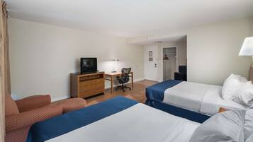 A hotel room with two beds, a desk, a chair, a television, and a wardrobe.
