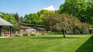 A hotel with a covered outdoor seating area, a swimming pool, and a well-maintained lawn. - Americas Best Value Inn Painted Post (Painted Post)