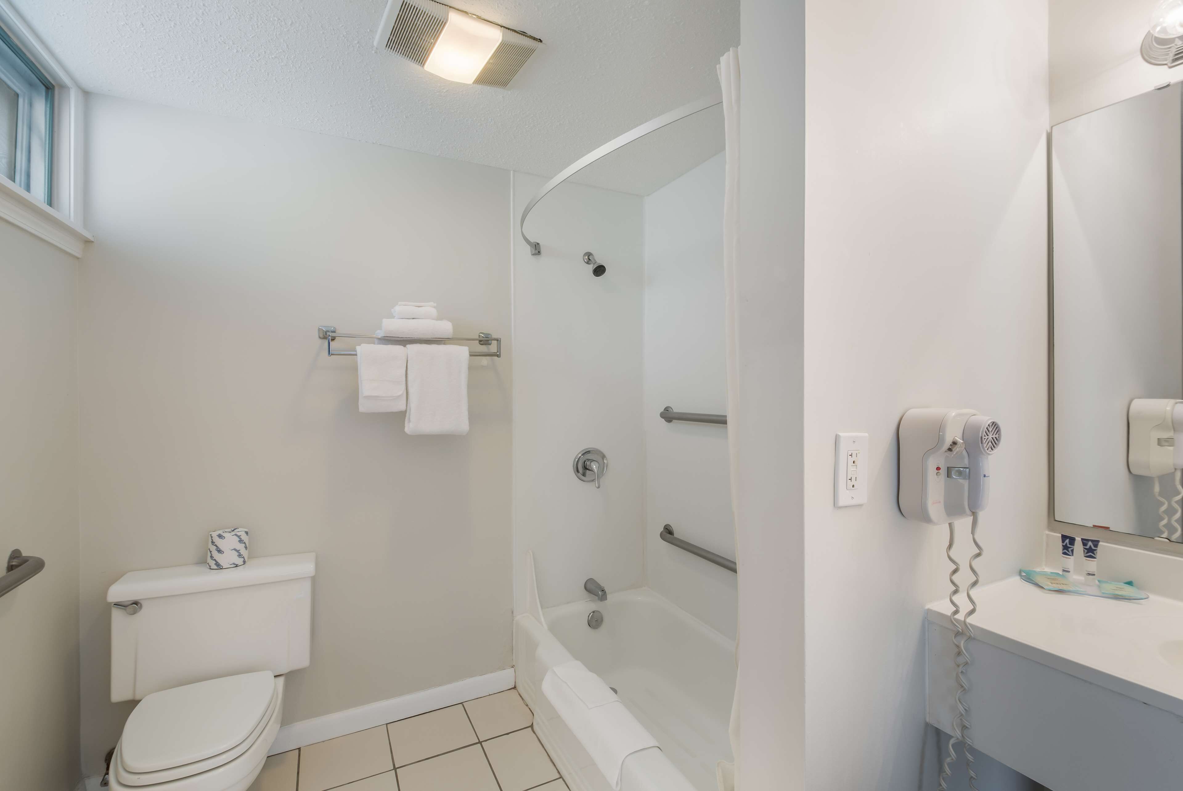 A bathroom with a toilet, a bathtub, a shower, and a sink with a mirror.