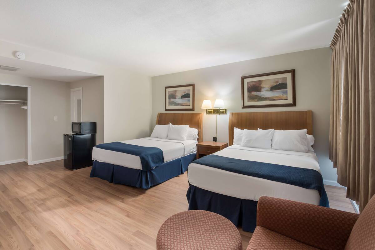 A hotel room with two beds, a desk, a chair, a TV, and a wardrobe.
