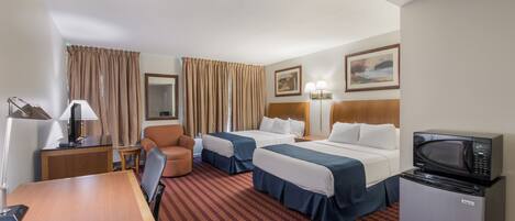 A hotel room with two beds, a desk, a chair, a small refrigerator, and a microwave.