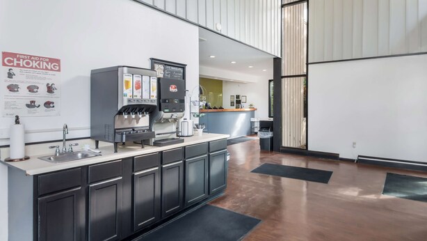 A modern kitchen area with a coffee machine, a sink, and a sign about first aid for choking. - Americas Best Value Inn Painted Post (Painted Post)