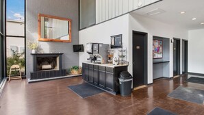 A modern lobby with a fireplace, coffee machines, and a bulletin board. - Americas Best Value Inn Painted Post (Painted Post)