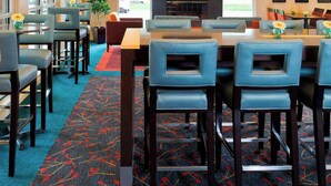 A hotel lobby with a high ceiling, a fireplace, a flat-screen TV, and a large dining table with chairs. - Residence Inn By Marriott Peoria (Peoria)