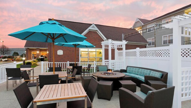 An outdoor patio area with wooden tables and chairs, a round seating area, and a large blue umbrella. - Residence Inn By Marriott Peoria (Peoria)