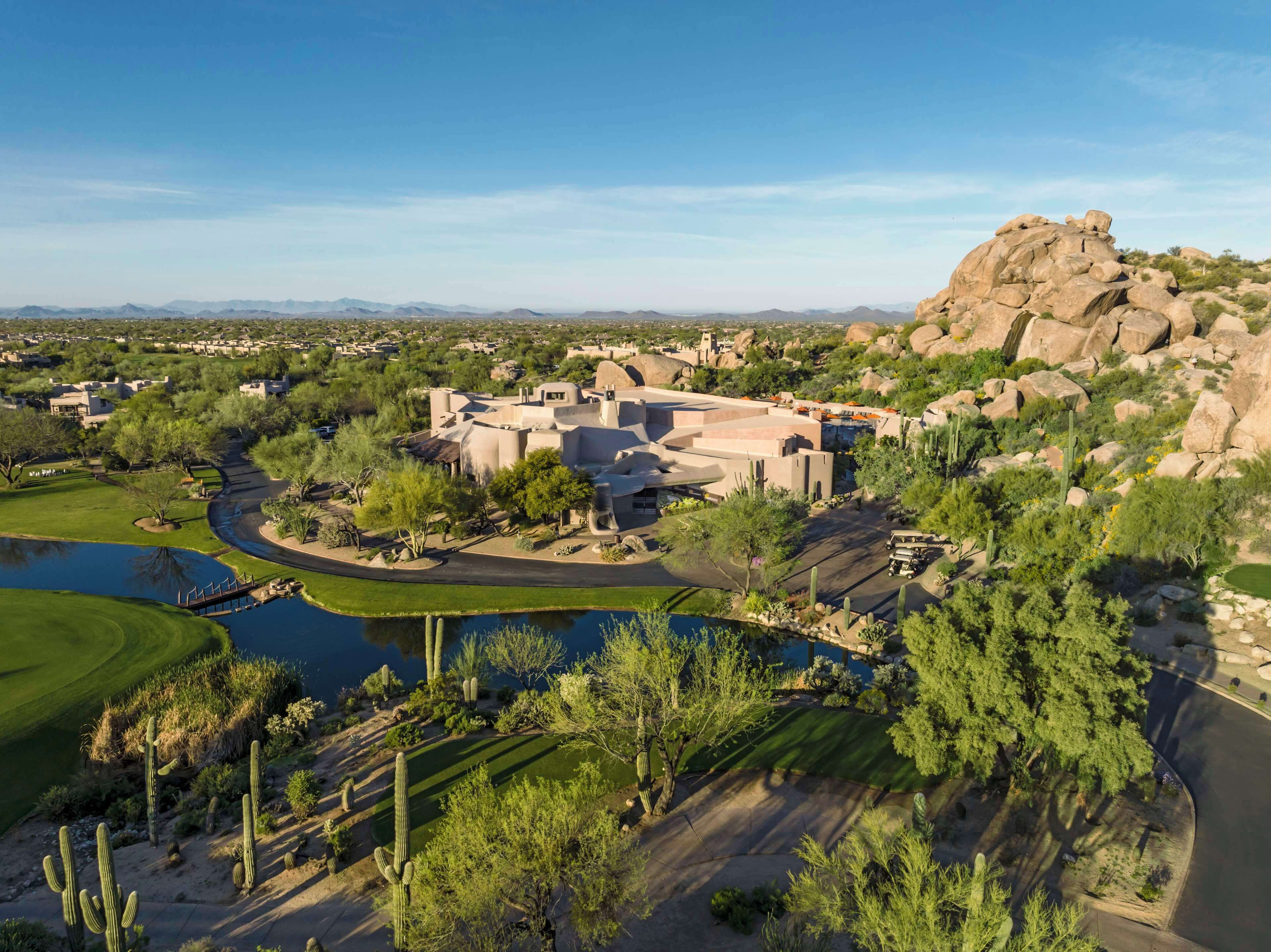 A resort with a pool, cacti, and a large rock formation.