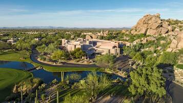 A resort with a pool, cacti, and a large rock formation.