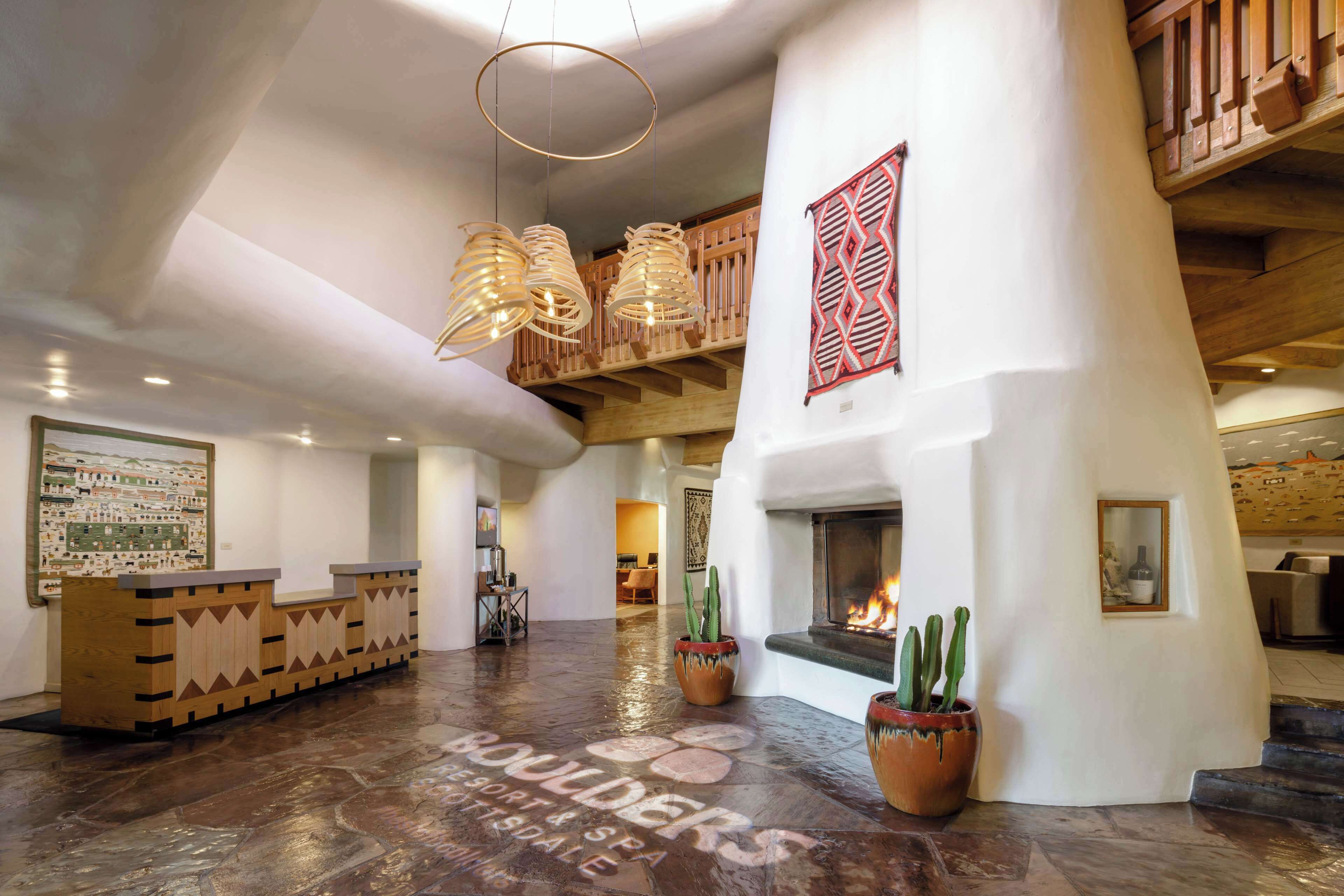Un hall d’entrée spacieux avec un comptoir d’accueil en bois, une cheminée et des cactus en pot.