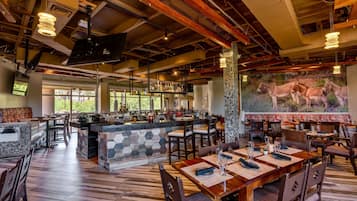 Un restaurante con zona de bar, suelo de madera y un mural de burros en la pared.