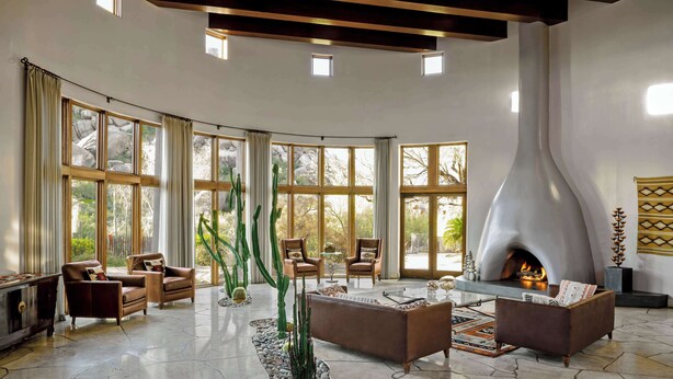 A spacious living room with a fireplace, large windows, and modern furniture. - Boulders Resort & Spa Scottsdale, Curio Collection by Hilton (Scottsdale)