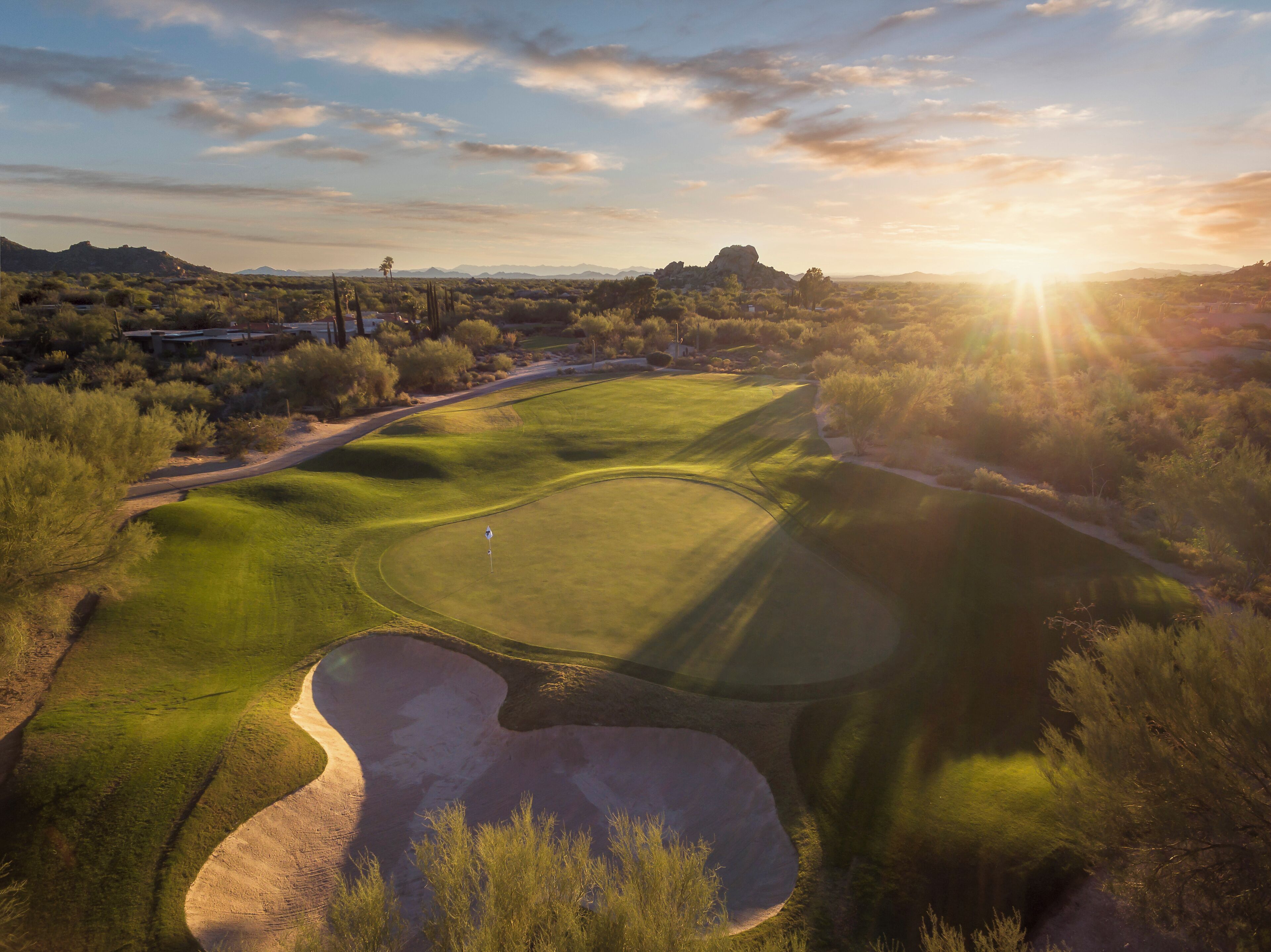 A golf course with a clear view of the green, sand bunkers, and surrounding landscape.