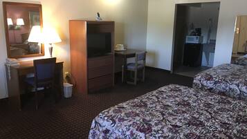 A hotel room with a desk, chair, television, and two beds with floral bedding.