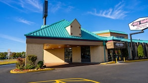 A City Café with a green roof, a sign indicating it's open 24 hours, and a parking lot with marked spaces.