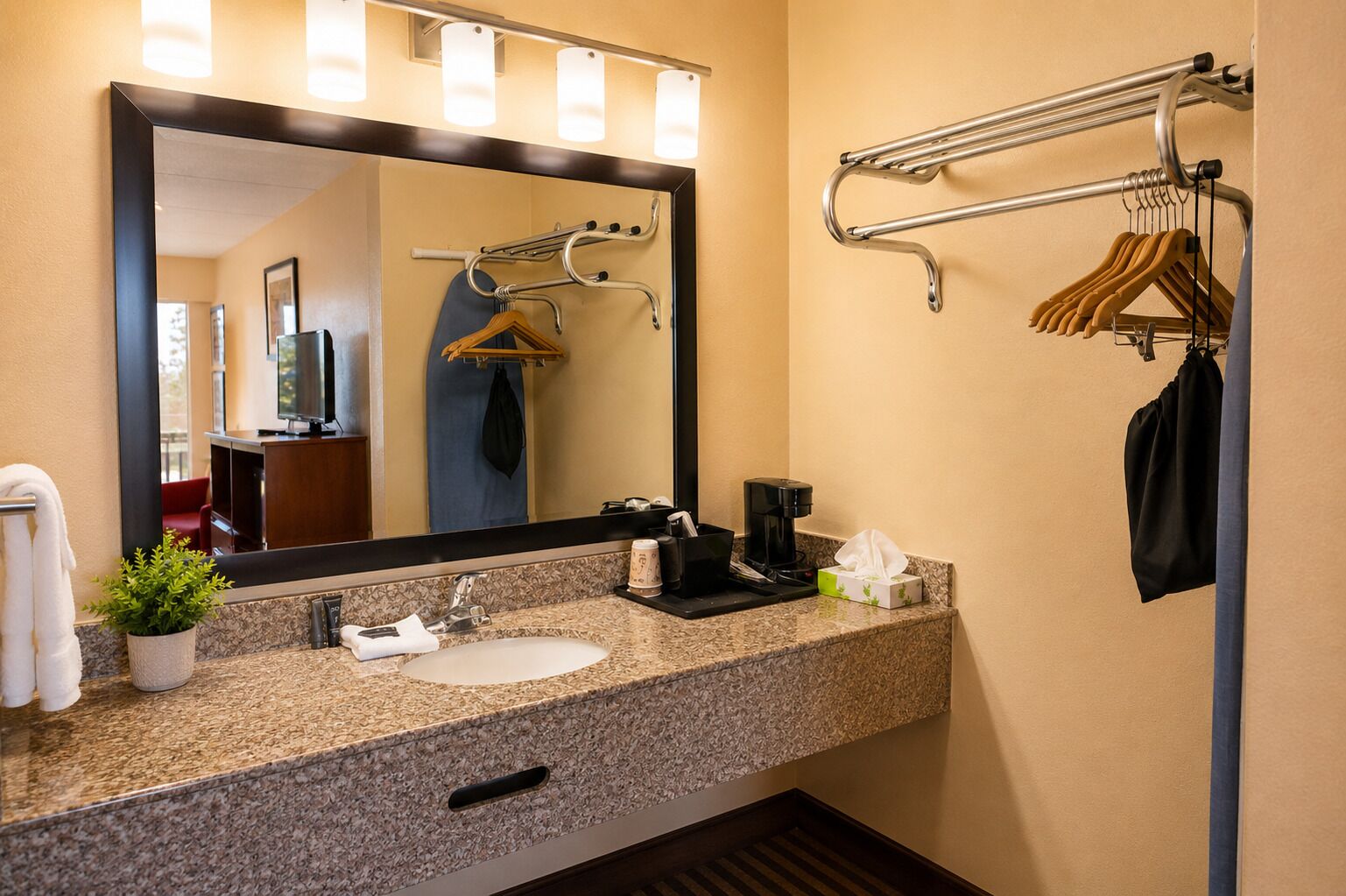 Une salle de bain d’hôtel équipée d’un lavabo, d’un miroir, d’un porte-serviettes et d’une machine à café.