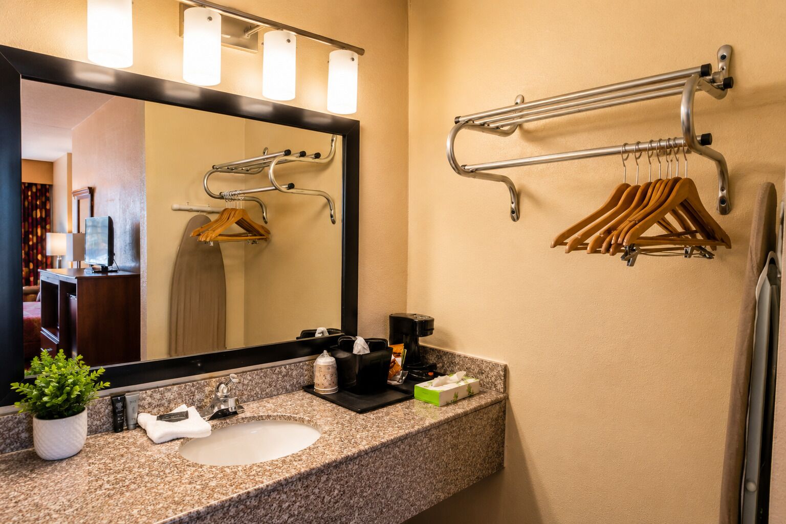Une salle de bain d’hôtel avec un comptoir en granit, un lavabo, un miroir, un porte-serviettes et un distributeur de serviettes.