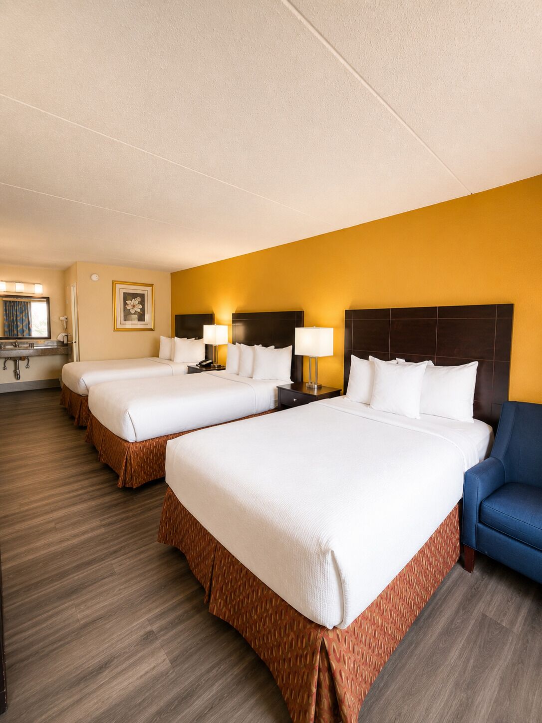 Ein Hotelzimmer mit zwei Betten, einer Sitzecke, einem Badezimmer und einem Flur.