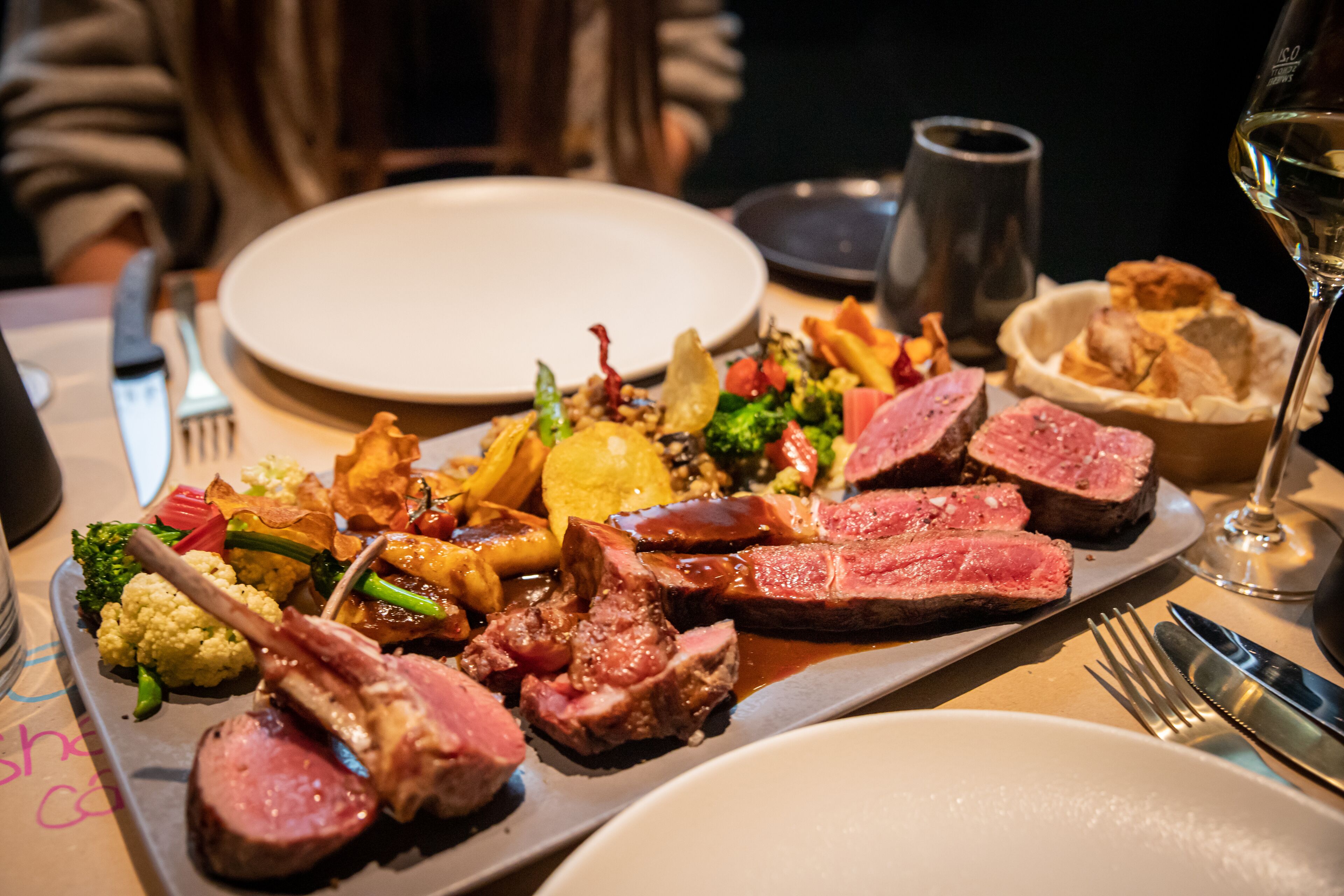 Prato de comida com bife, legumes e batatas.