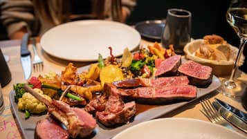 Prato de comida com bife, legumes e batatas.