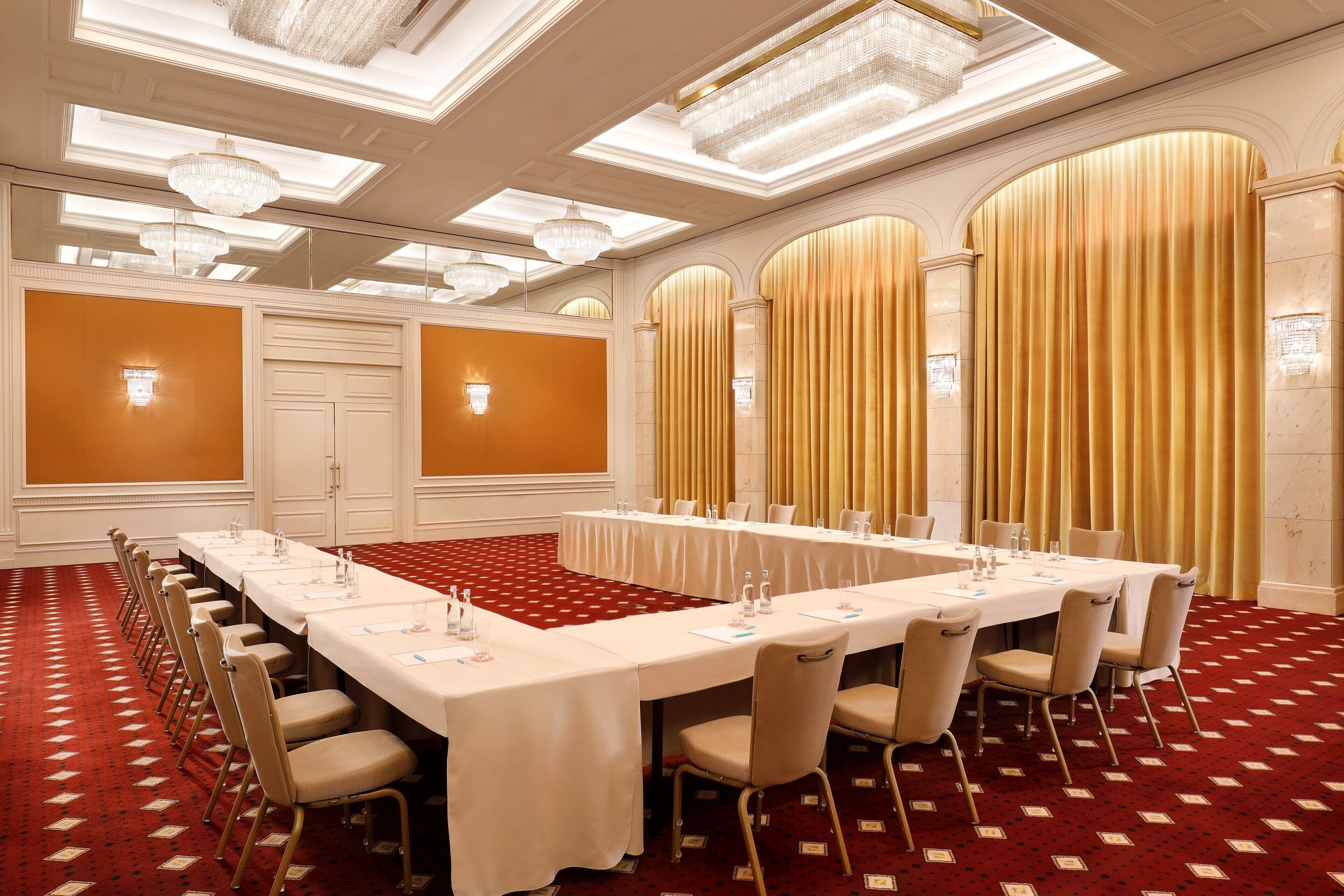 A conference room with a long table, chairs, and a red carpet.