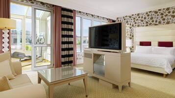 Ein Hotelzimmer mit Bett, Fernseher, Sofa, Glastisch und Blick nach draußen.