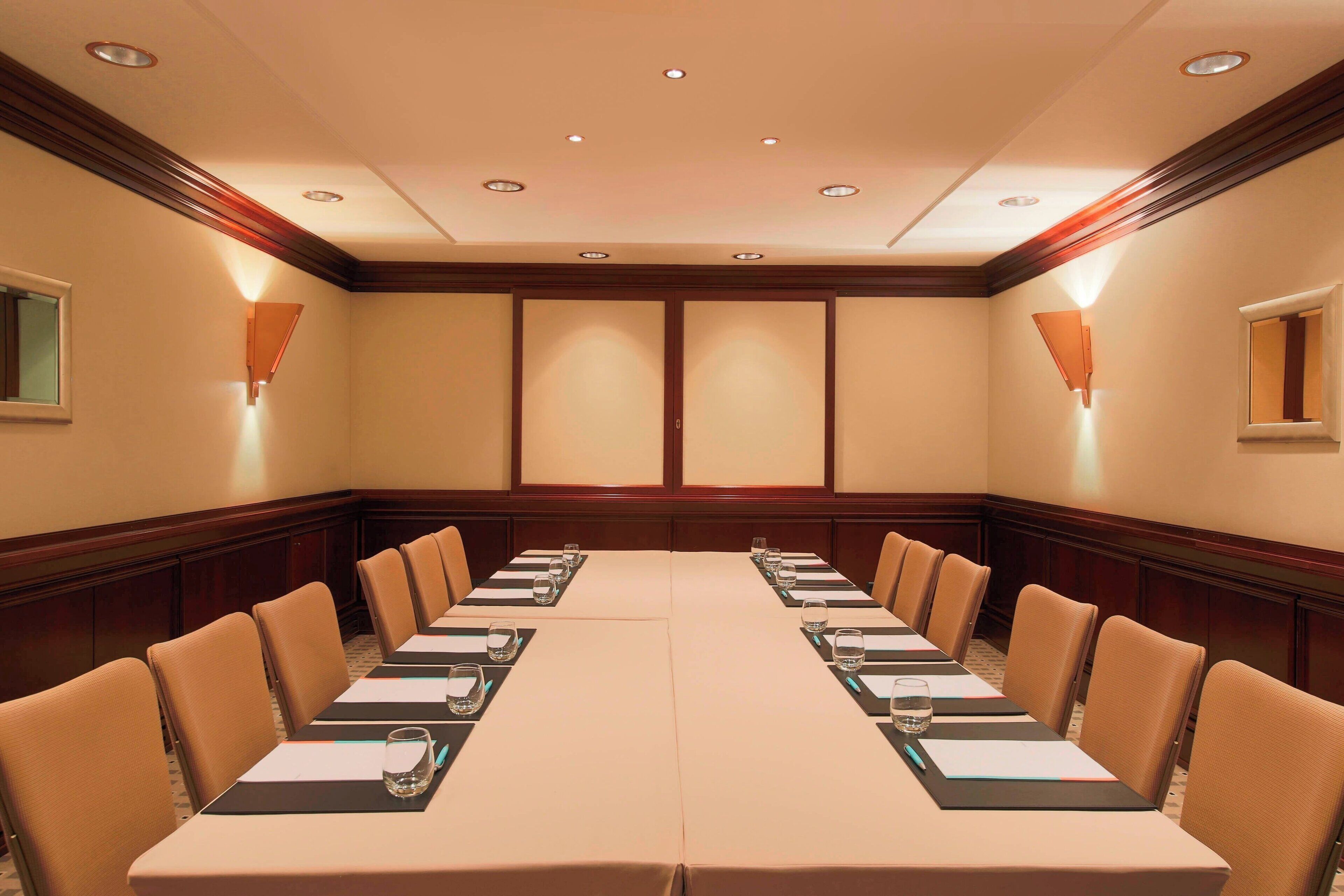 A conference room with a long table, chairs, and recessed lighting.